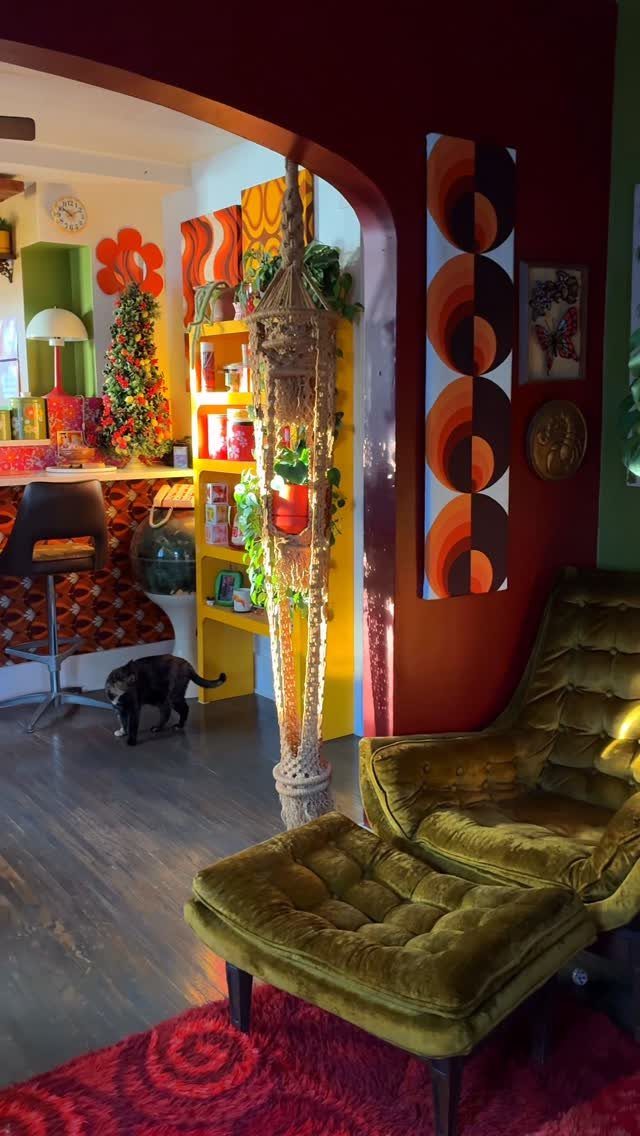Green velvet tufted chair and ottoman in a colorful 70s eclectic living room