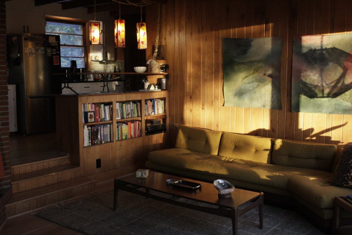Mustard yellow tufted sofa and wood coffee table in a wood-paneled living room.