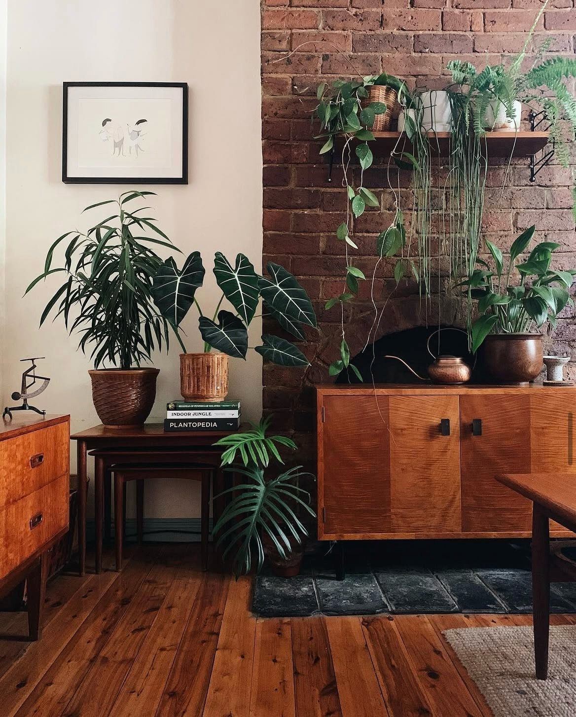 Mid-century modern living room with wooden furniture, houseplants, and a red brick wall.