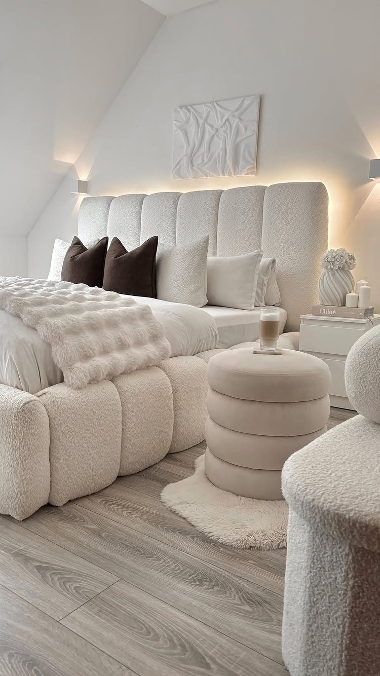 White textured bed with brown pillows and a small fluffy white rug.