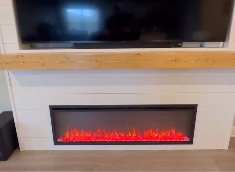 White shiplap wall with a built-in electric fireplace and mounted television above.