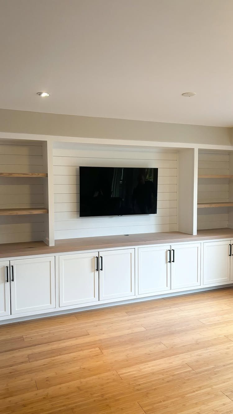 White shiplap accent wall with a mounted TV and white built-in cabinetry.