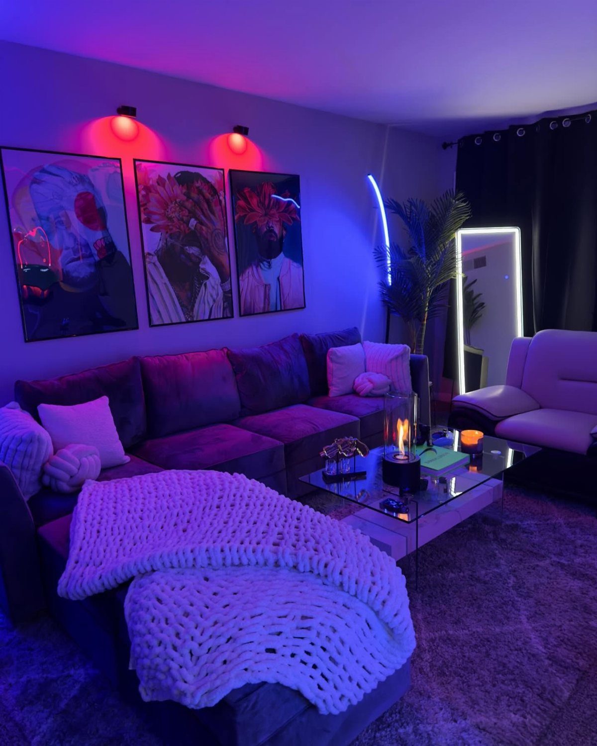 Purple velvet sectional sofa in a room with neon lighting and wall art.