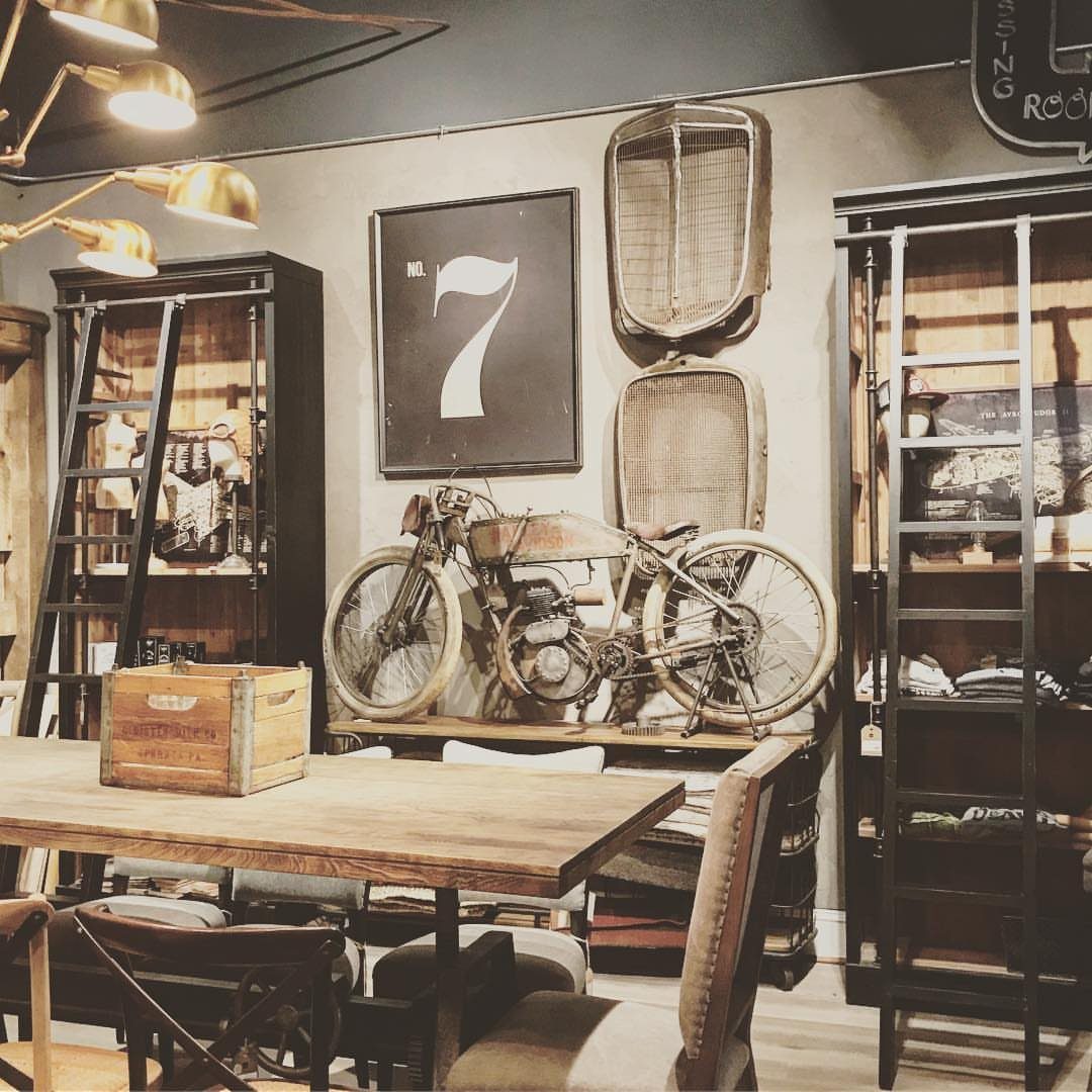 Vintage motorcycle displayed in a room with leather chairs and wooden furniture.