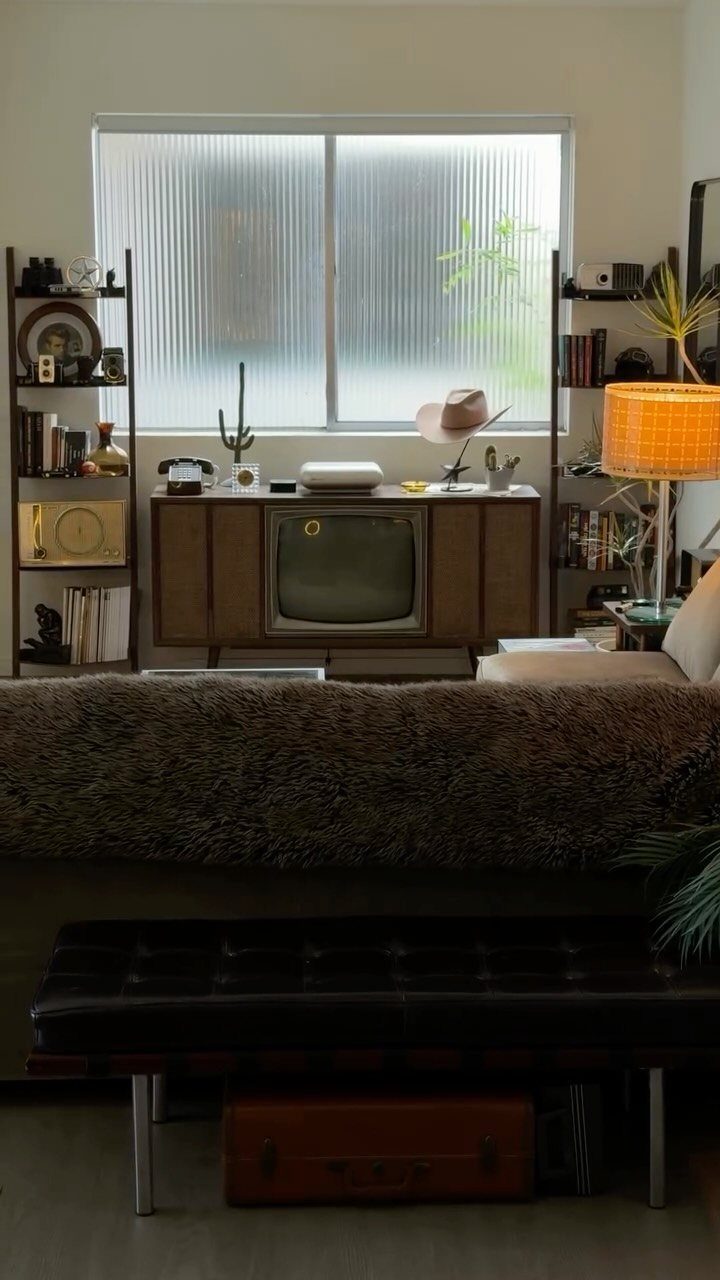 Mid-century modern wooden sideboard with a vintage television in a styled living room.