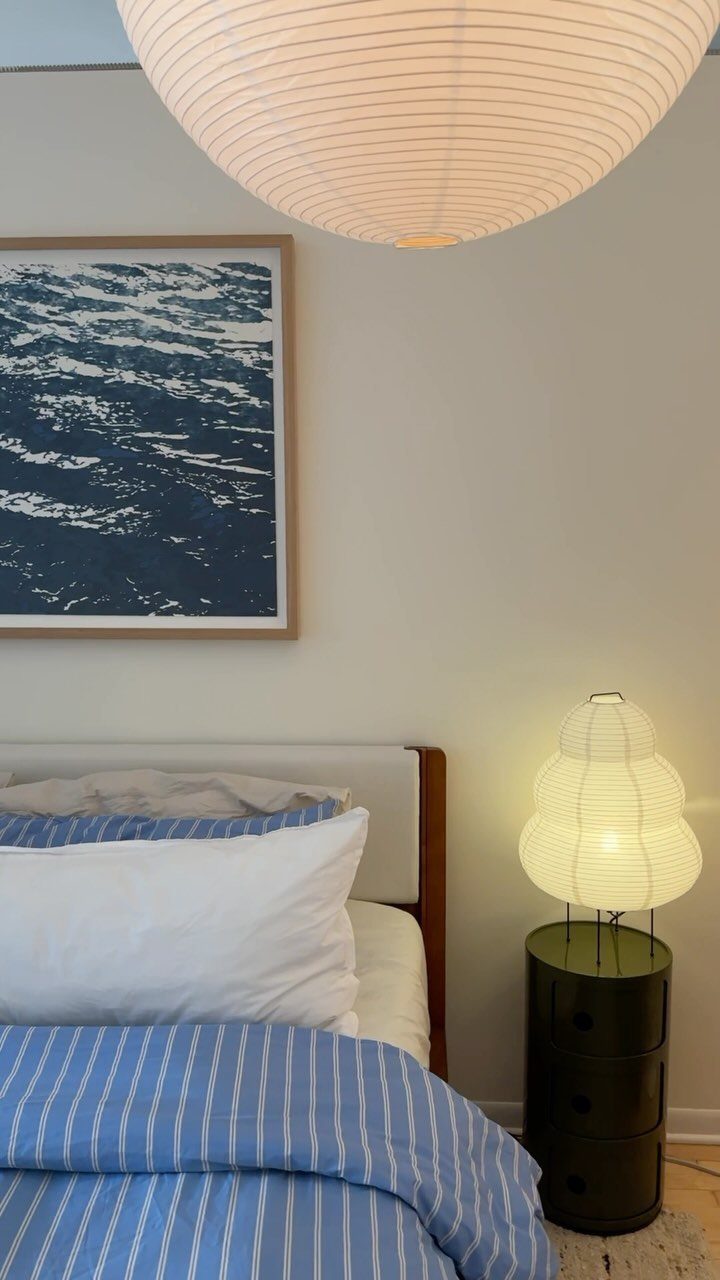Framed blue abstract wall art hanging above a bed with striped blue bedding.