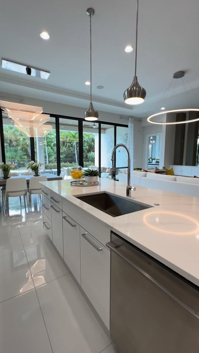 Modern white kitchen island opening into a dining area with large glass doors.
