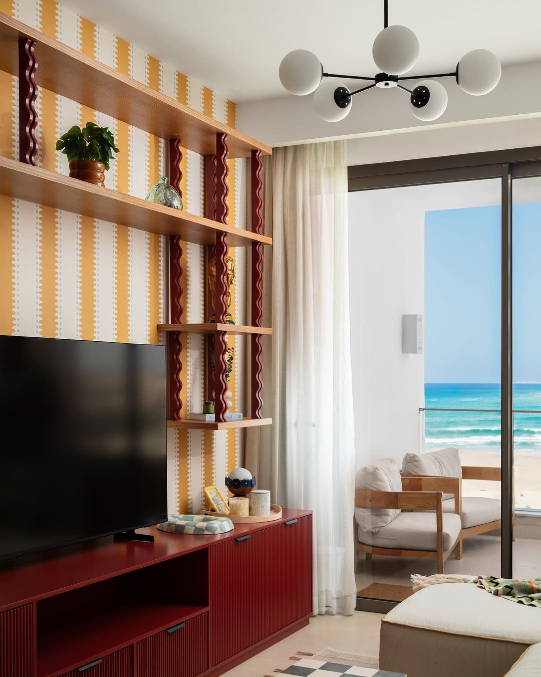 Yellow and white striped wallpaper in a coastal living room overlooking the ocean.