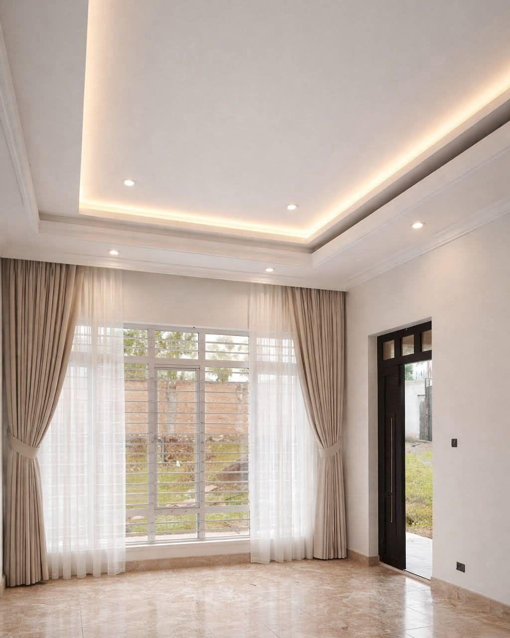 Layered beige and sheer white curtains framing a large window in a bright room.