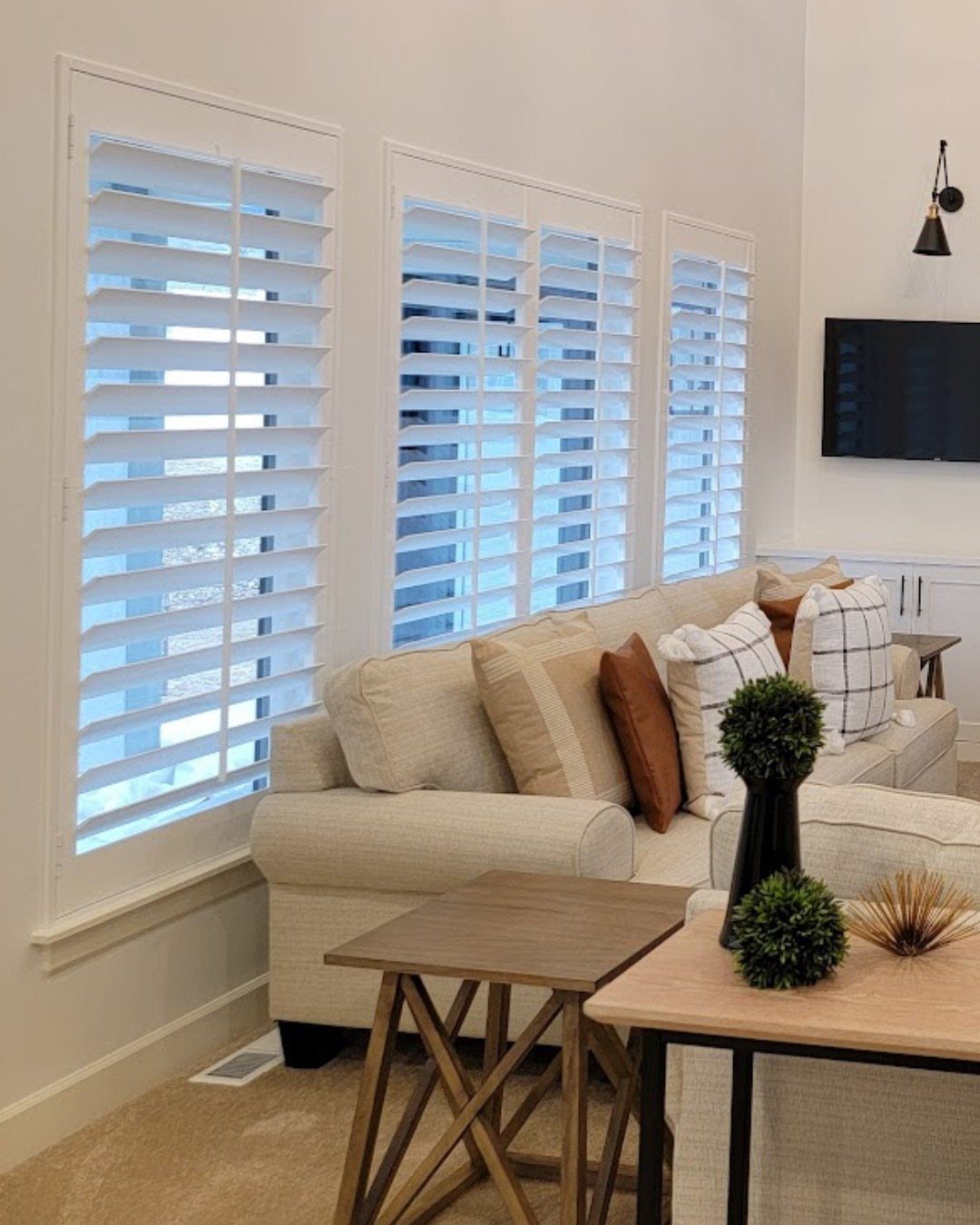 White plantation shutters on three large windows in a bright living room