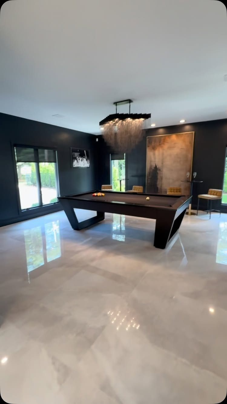 Modern black pool table in a room with dark walls and polished floors