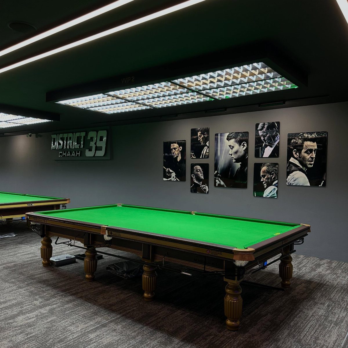 Green felt pool table in a modern room with gallery wall art.