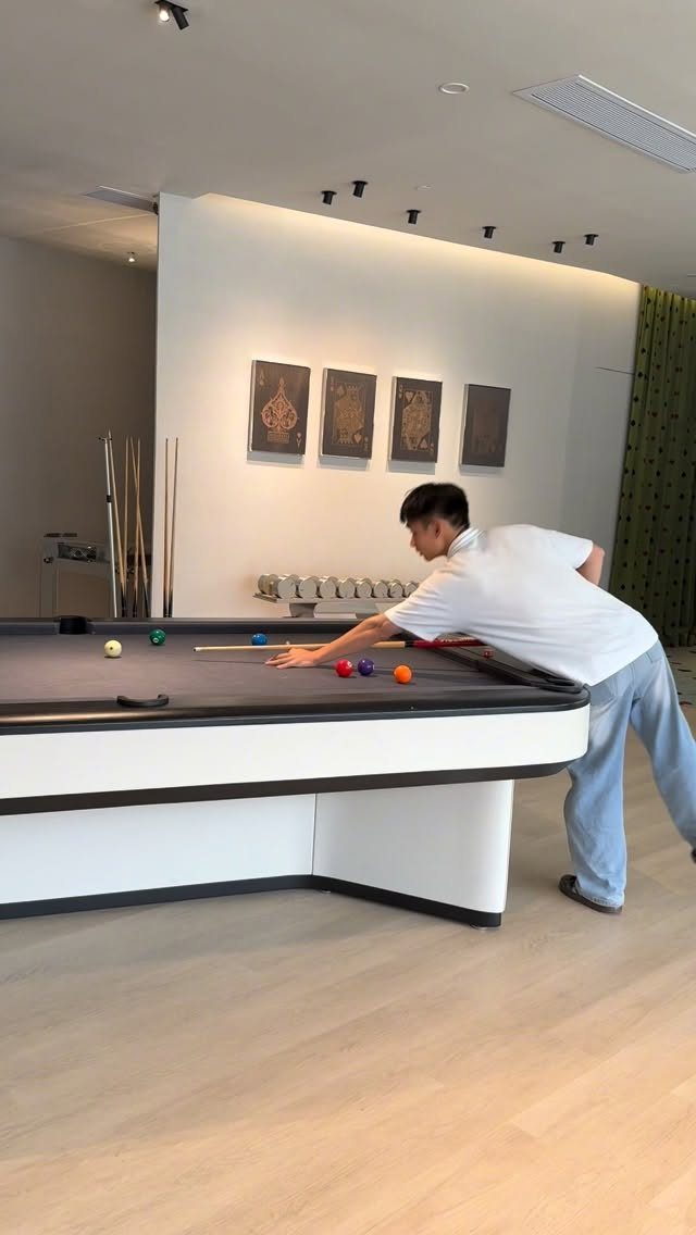 Man playing pool on a modern white billiard table in a minimalist room