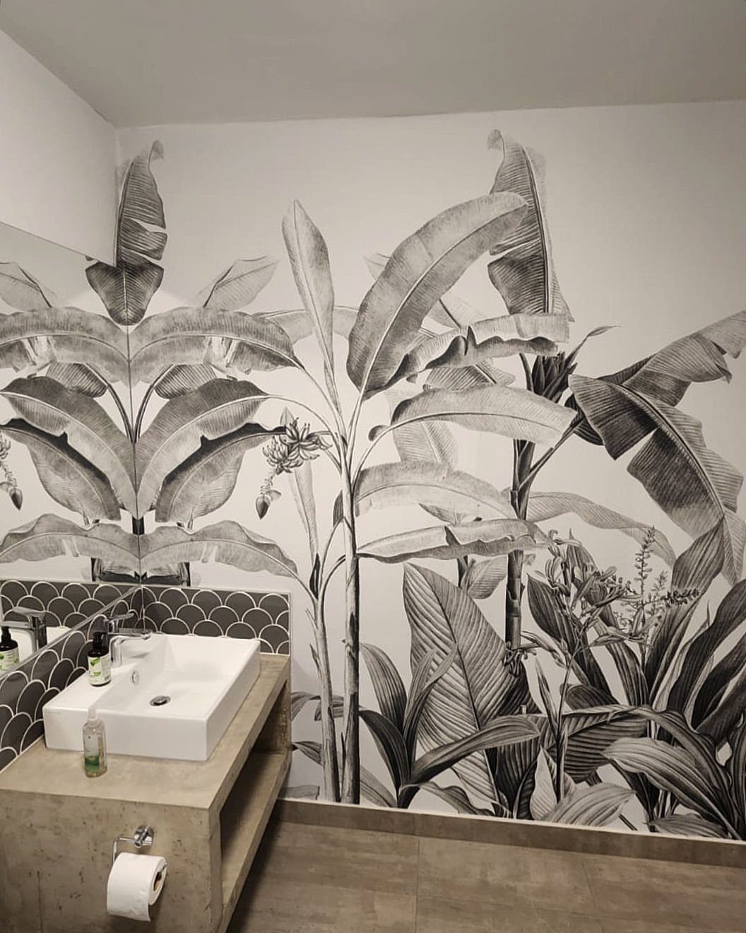 Tropical leaf mural in black and white decorating a modern bathroom wall.