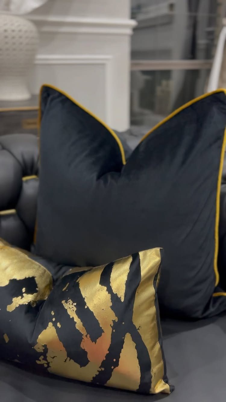 Black velvet pillows with gold piping and gold animal print on a sofa