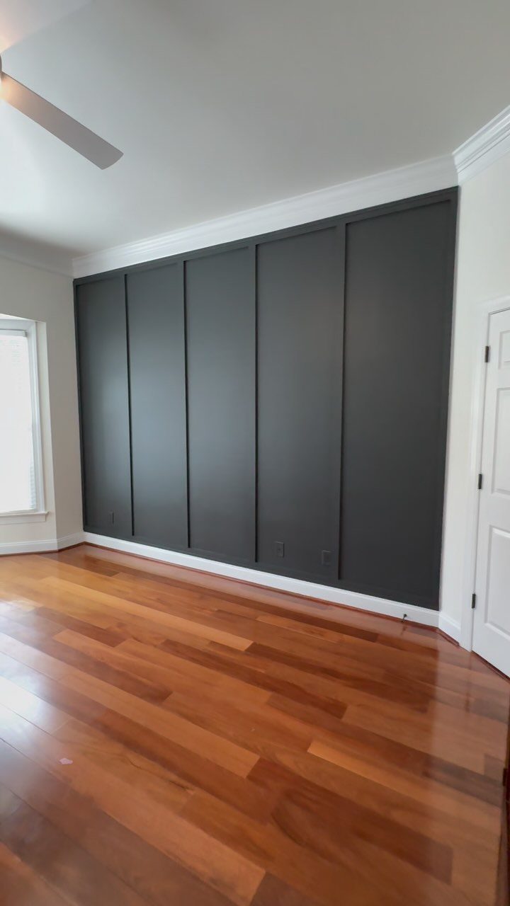 Dark grey board and batten wall with vertical strips and hardwood floors.
