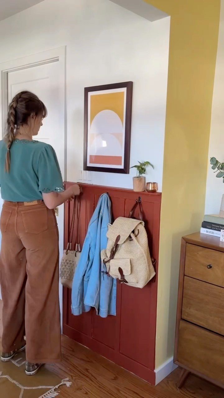 Woman standing by a red board and batten wall panel used as coat rack.