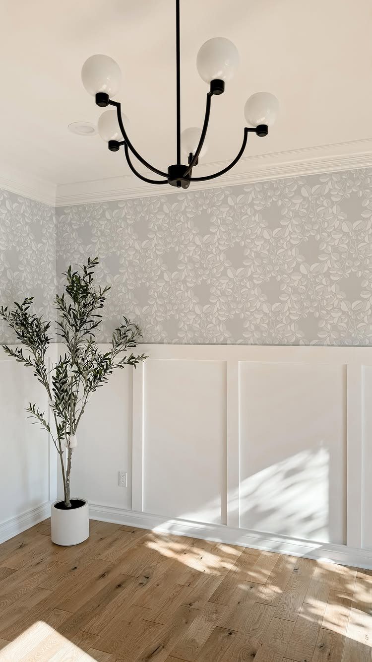 White board and batten wainscoting with floral wallpaper and a potted olive tree.