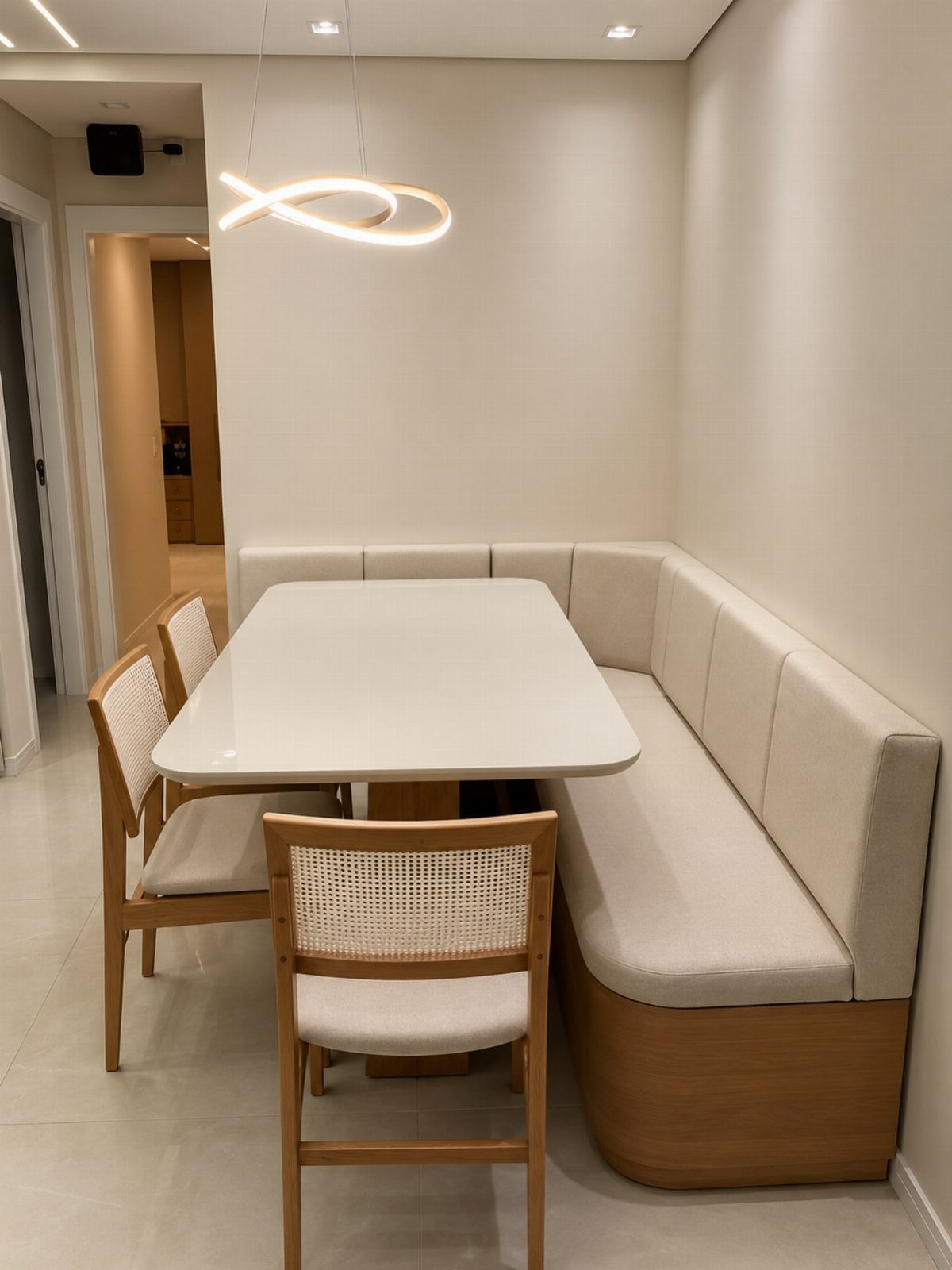 L-shaped built-in dining bench with cream cushions and a white rectangular table.