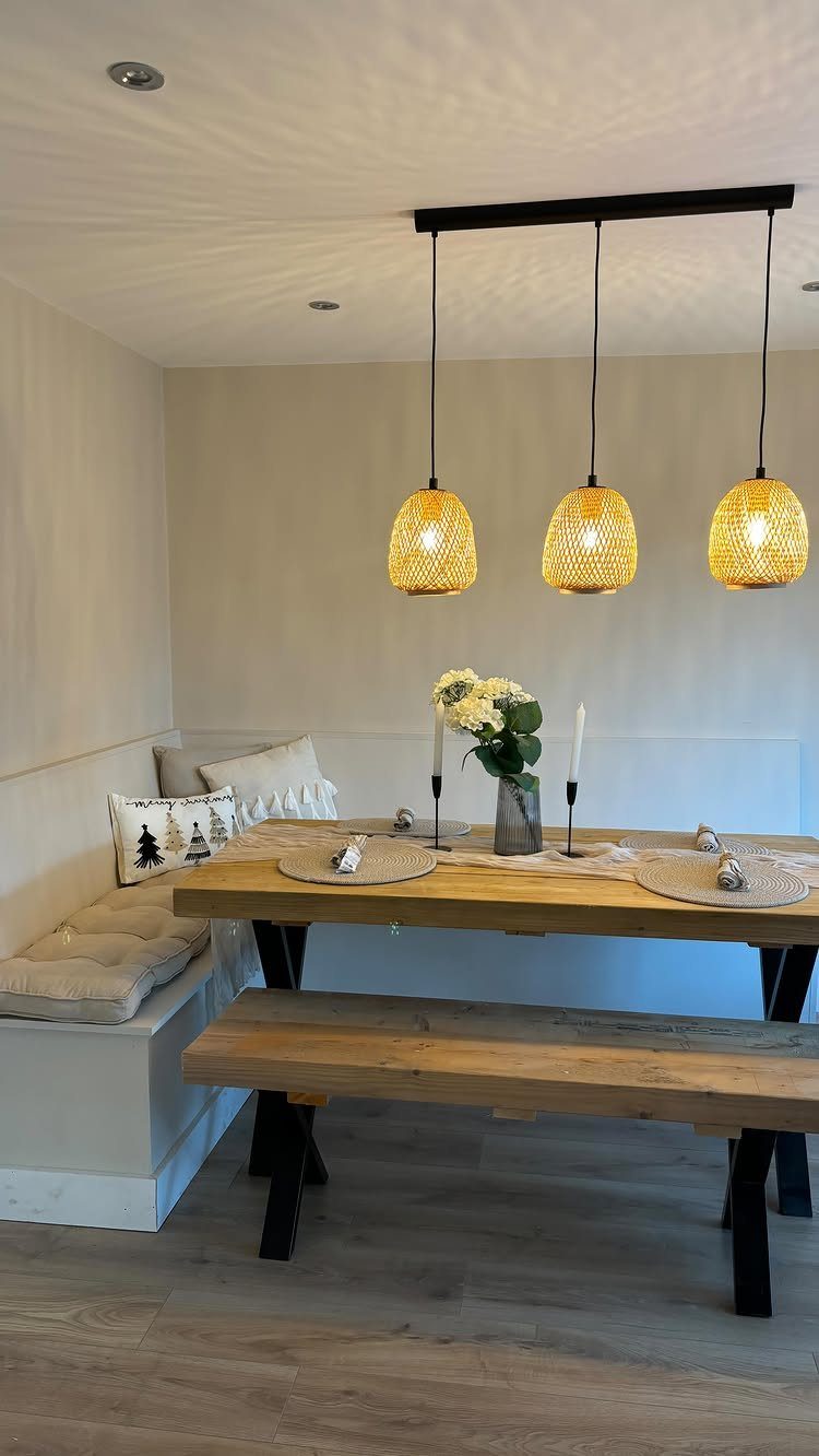Built-in dining bench with cushions and a wooden table under woven pendant lights.