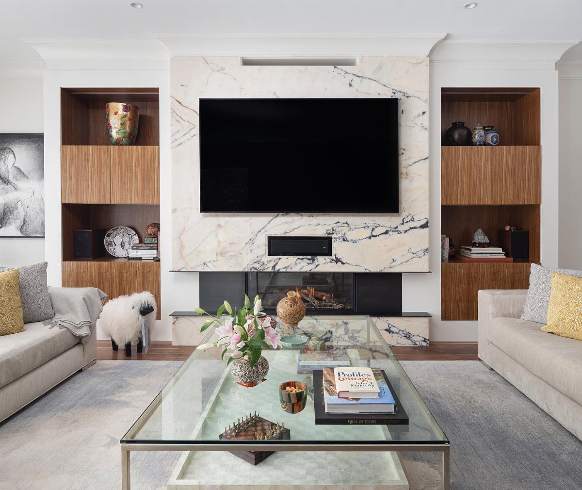 Modern entertainment center with marble fireplace surround and built-in wooden shelving units.