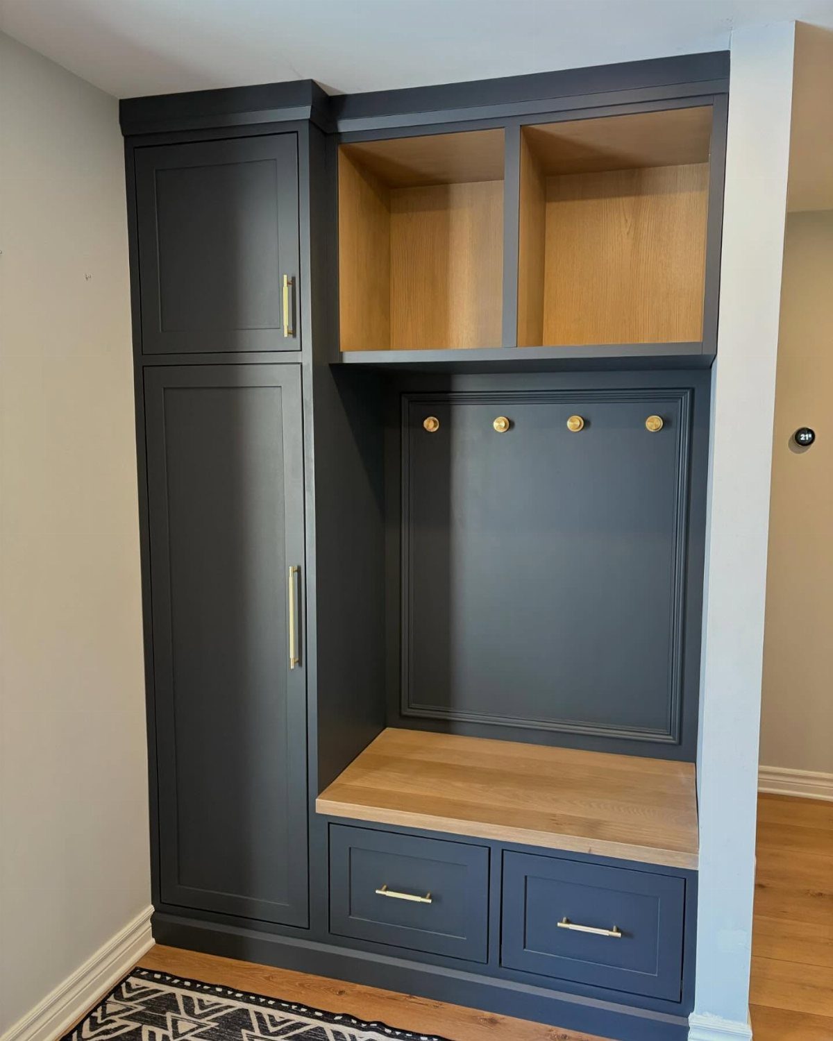 Dark blue built-in hall tree with wood bench, gold hooks, and storage cabinets.