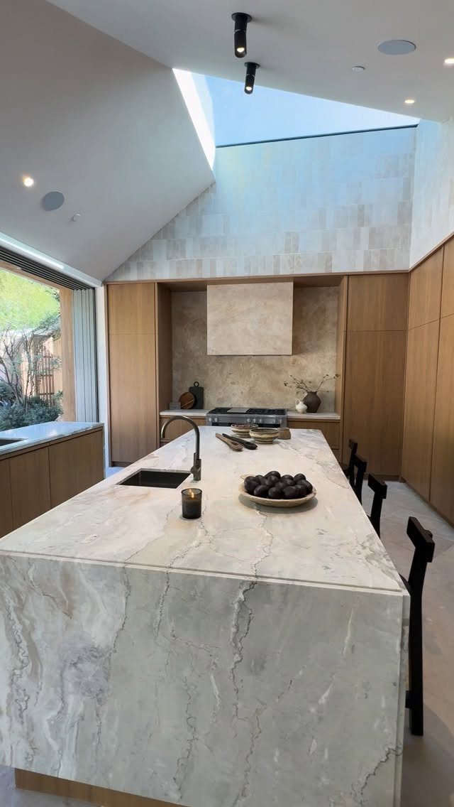 Modern kitchen with a white marble island and a large ceiling skylight.