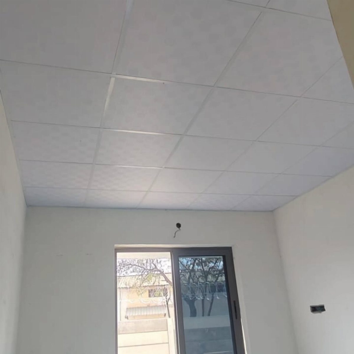 White drop ceiling tiles in a grid pattern installed in an empty room.