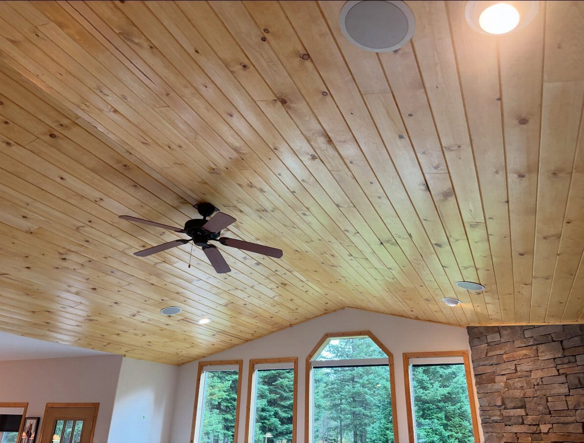 Wooden tongue and groove planks covering a vaulted ceiling with a brown fan.