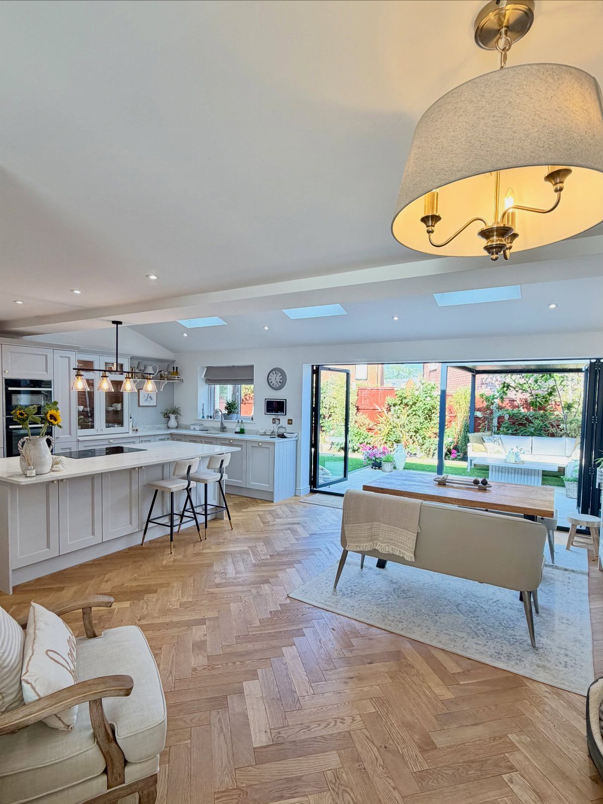 Open-concept kitchen and living area with white cabinetry and herringbone wood floors.