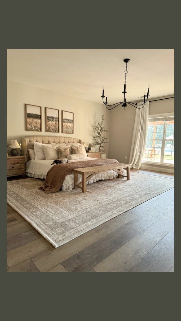 Upholstered bed and wooden bench on a large patterned rug in a neutral bedroom.