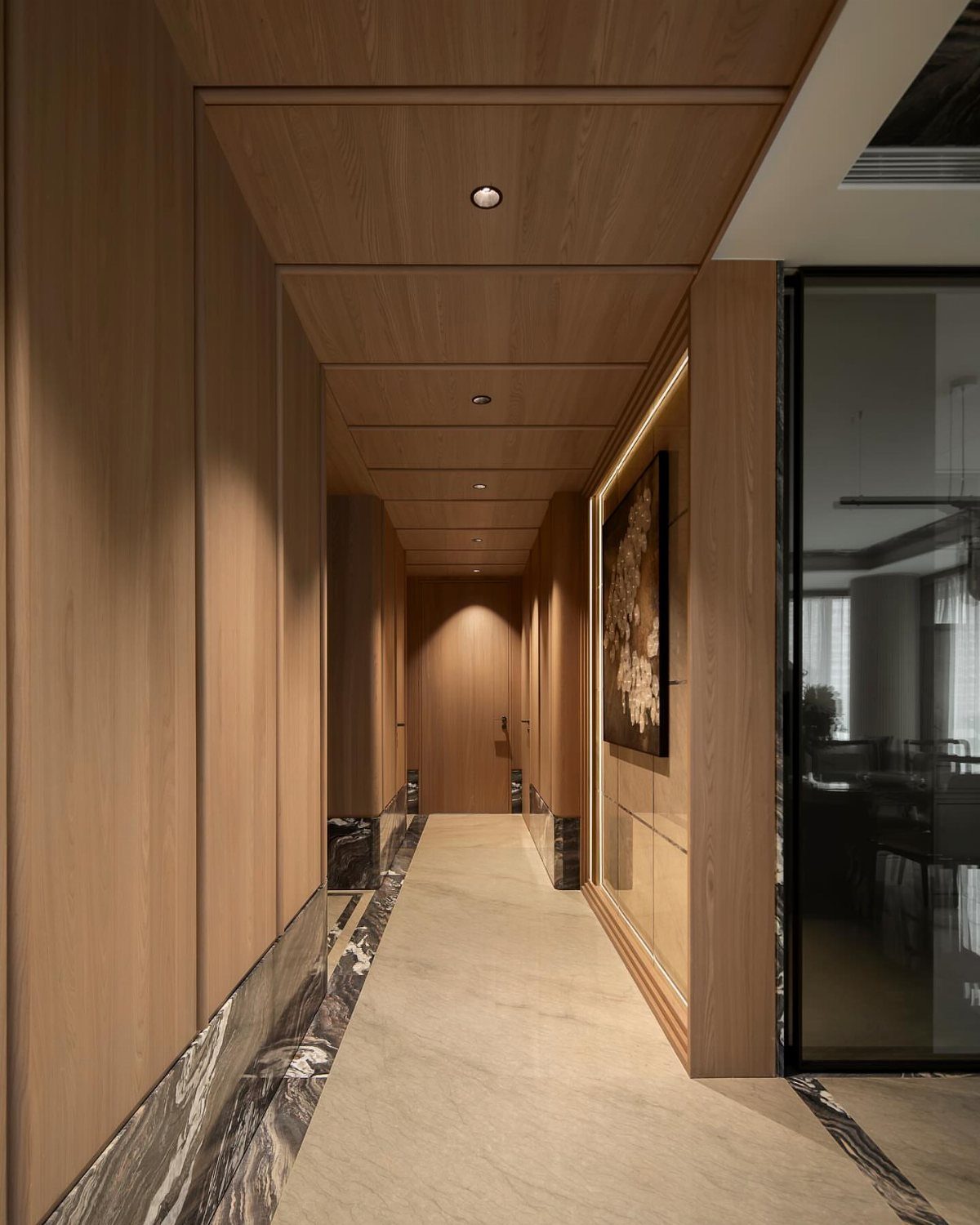 Luxury hallway with light wood paneling, stone flooring, and recessed ceiling lighting.