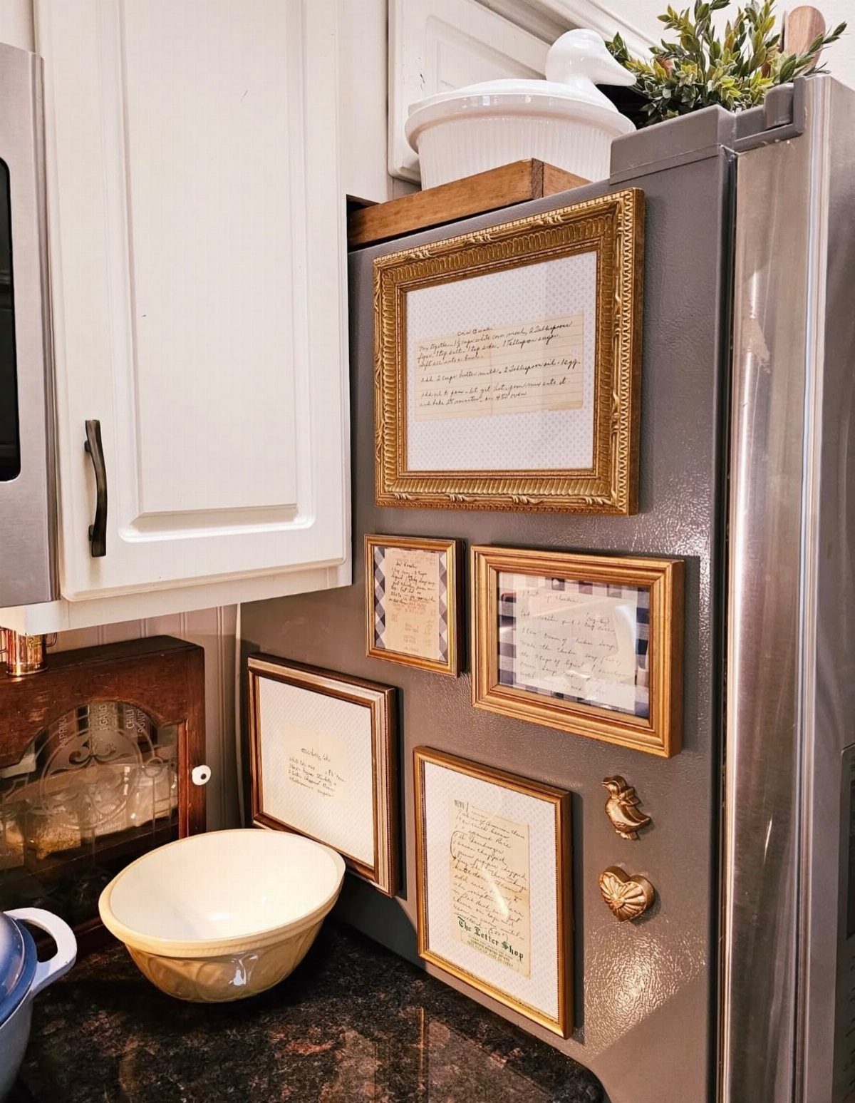 Gold-framed recipes and notes displayed on the side of a stainless steel refrigerator.