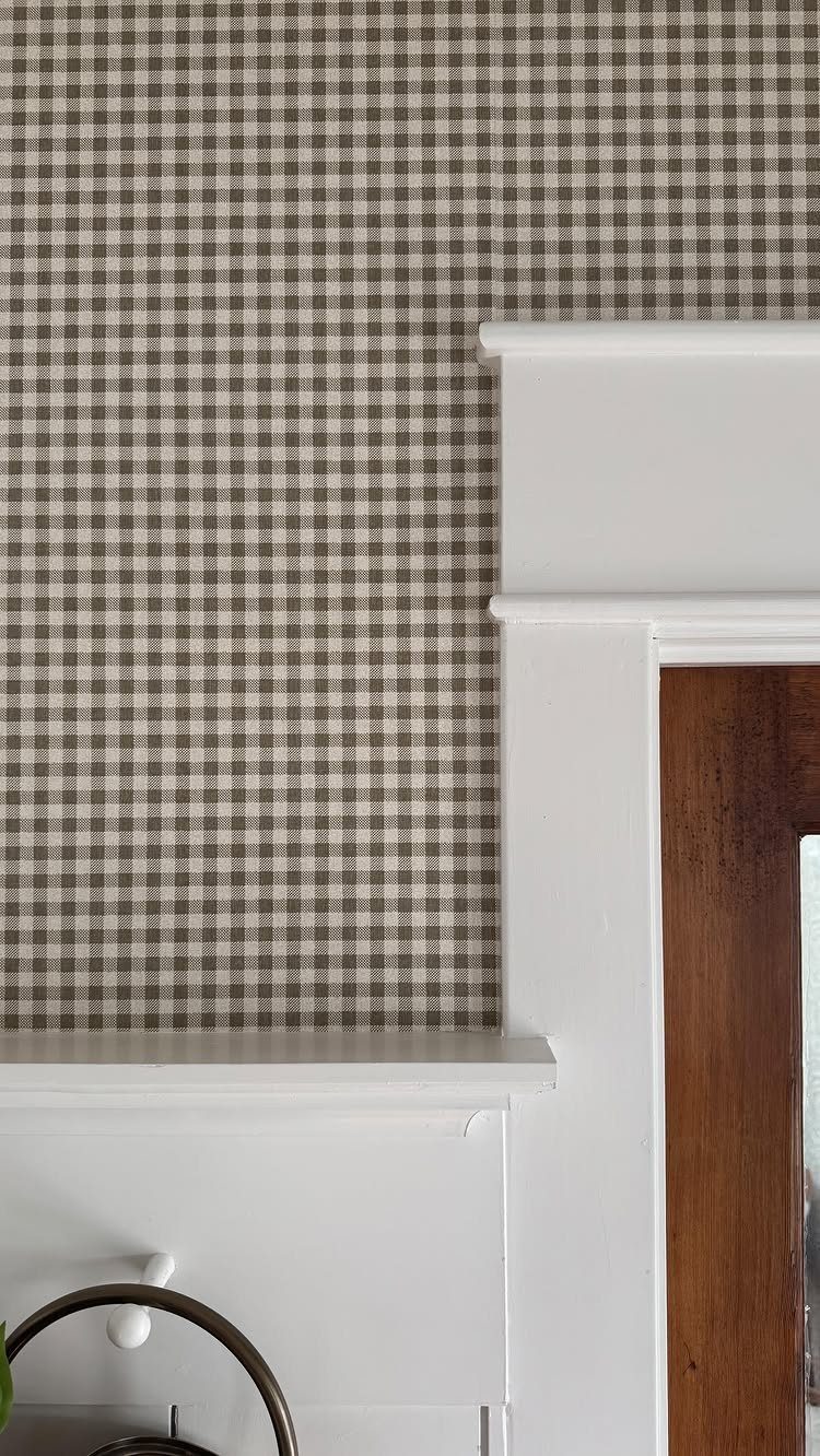 Gingham patterned wallpaper with white wooden trim and a dark wood doorway.