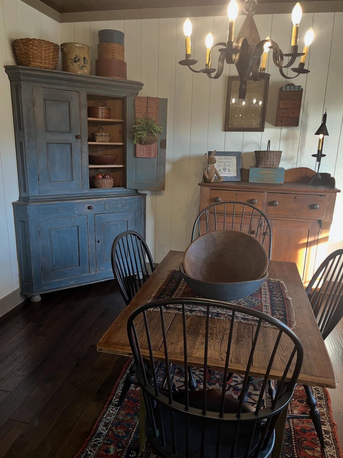Rustic dining room with a blue vintage hutch, wooden table, and black chairs.