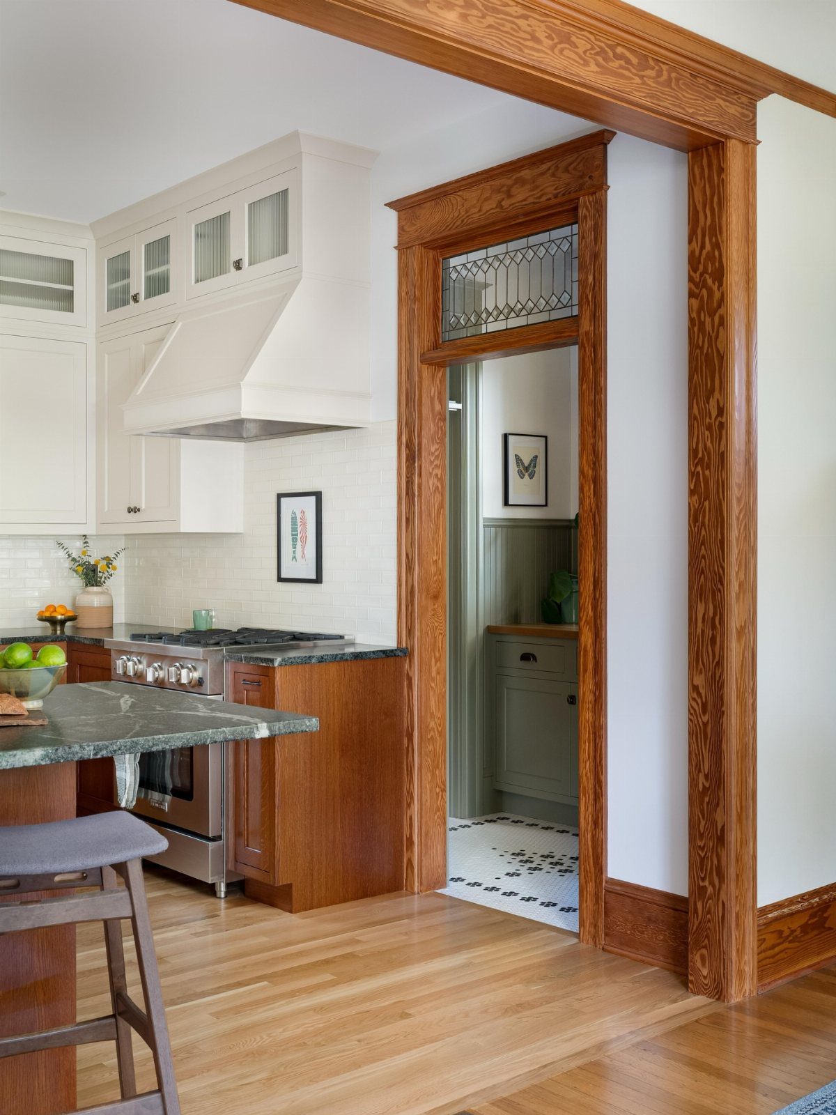 Kitchen interior with white cabinets, dark countertops, and heavy oak wood trim and flooring.