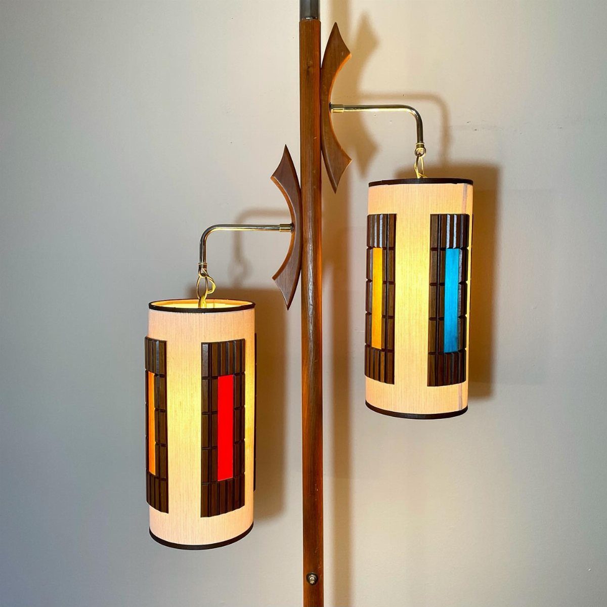 Mid-century modern floor lamp with wooden accents and colorful stained glass cylindrical shades.