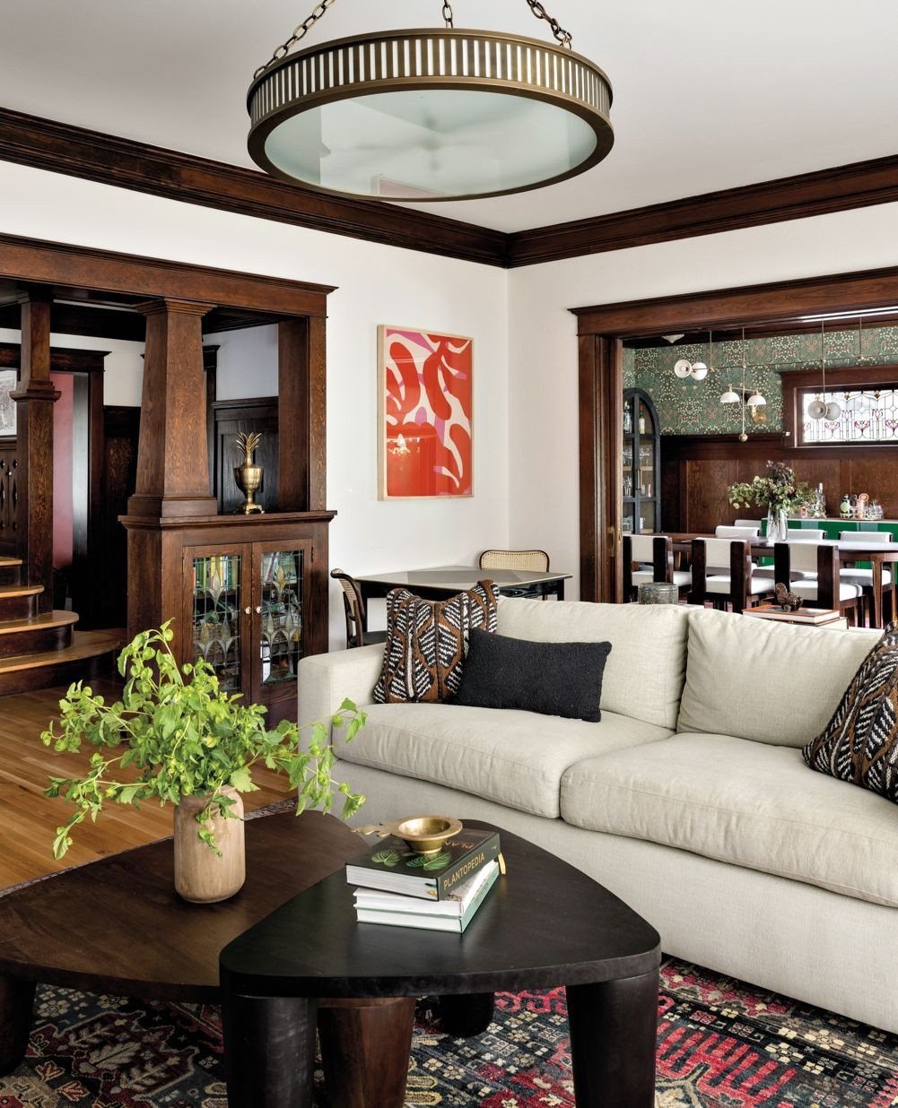 Living room with dark wood trim, cream sofa, and large circular pendant light.