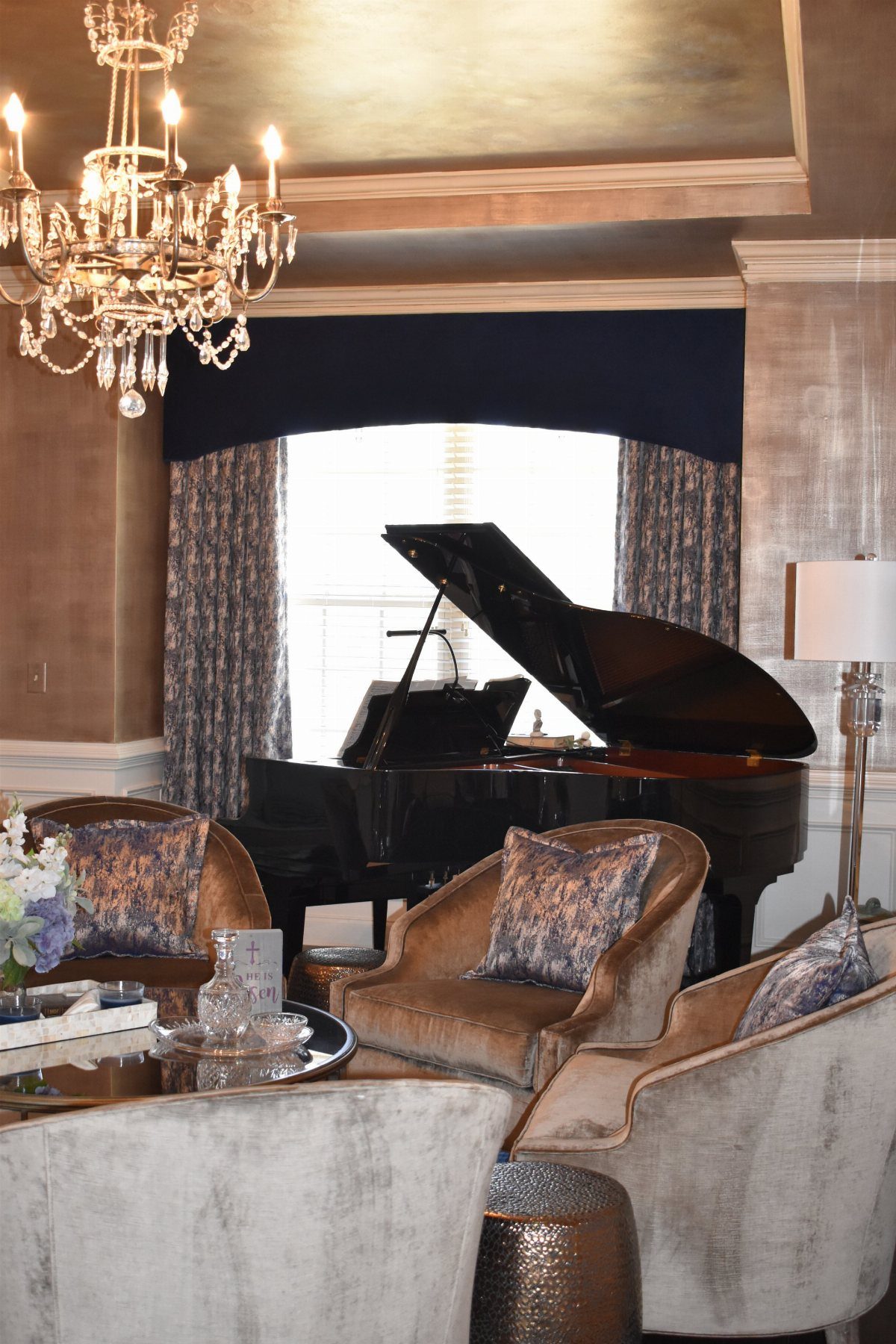 Dark blue arched valance and patterned curtains above a black grand piano