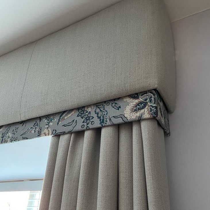 Grey padded valance with floral trim and matching pleated curtains on a window.
