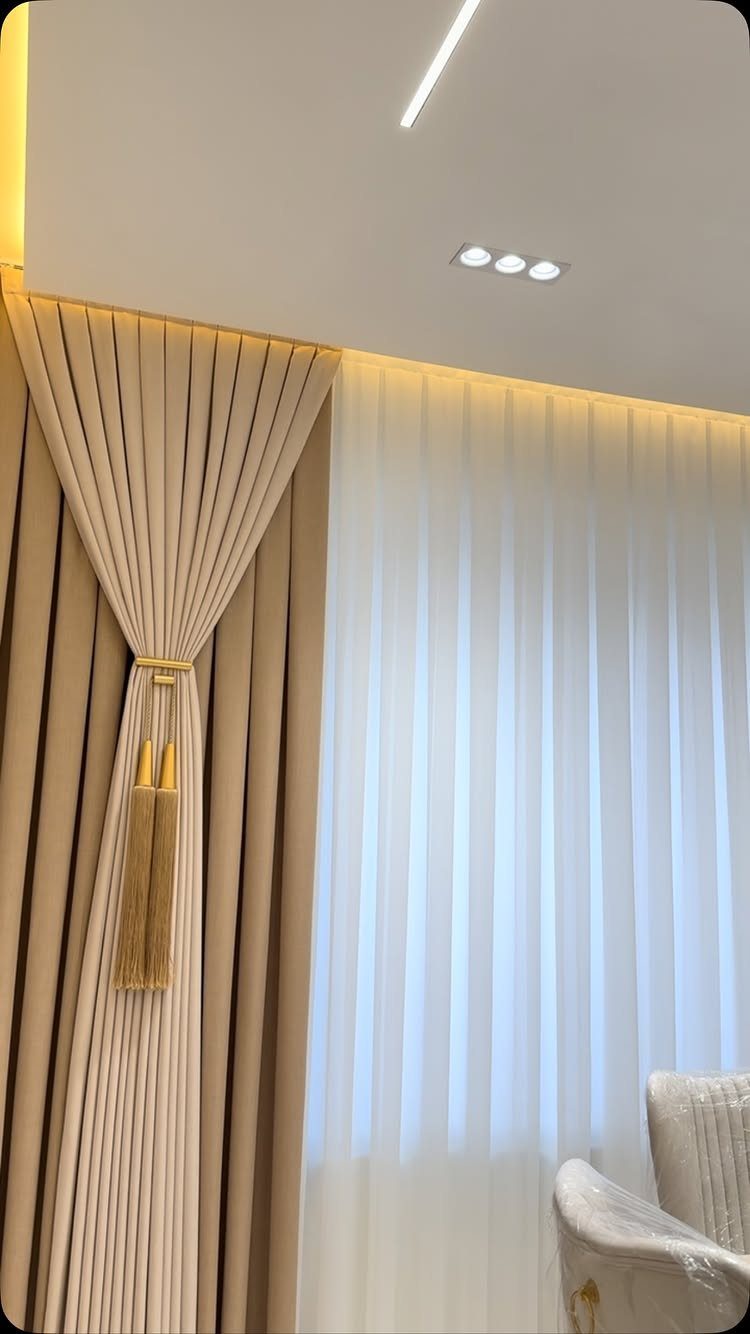 Beige and white curtains with a gold tassel tieback in a bright room