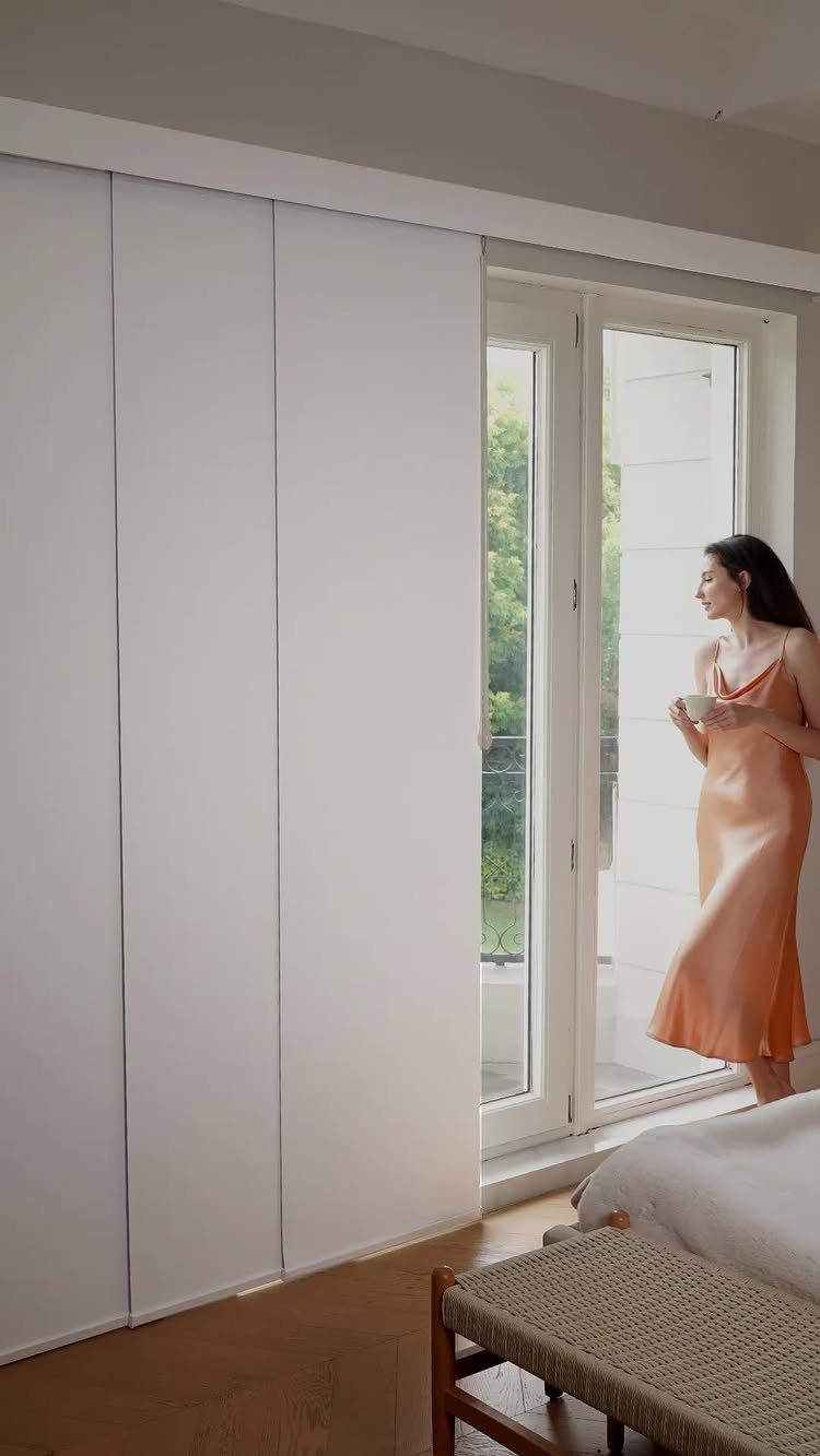 White panel track blinds covering a sliding glass door in a modern bedroom