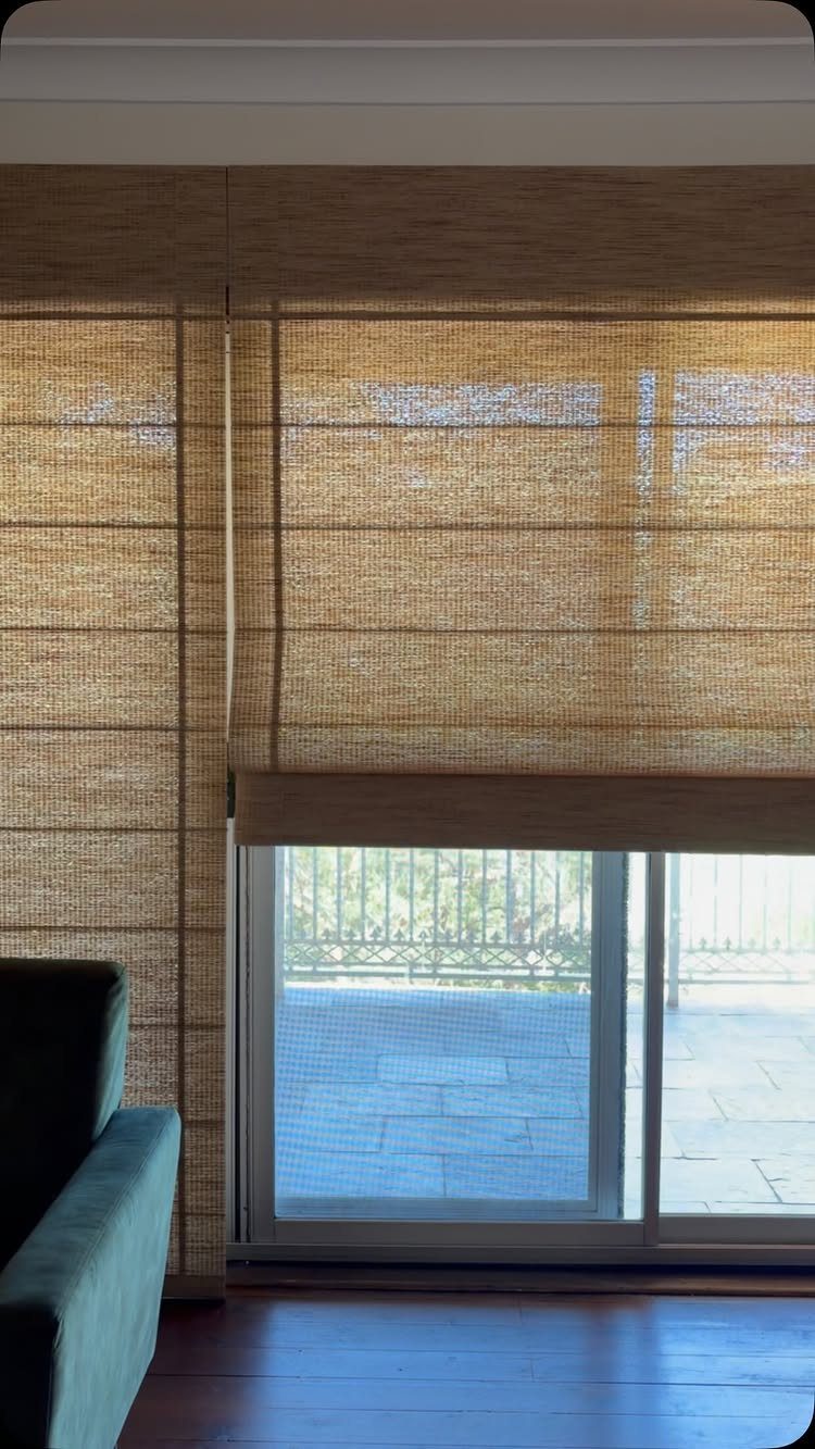 Beige woven bamboo roman shades on a sliding glass door leading to a patio
