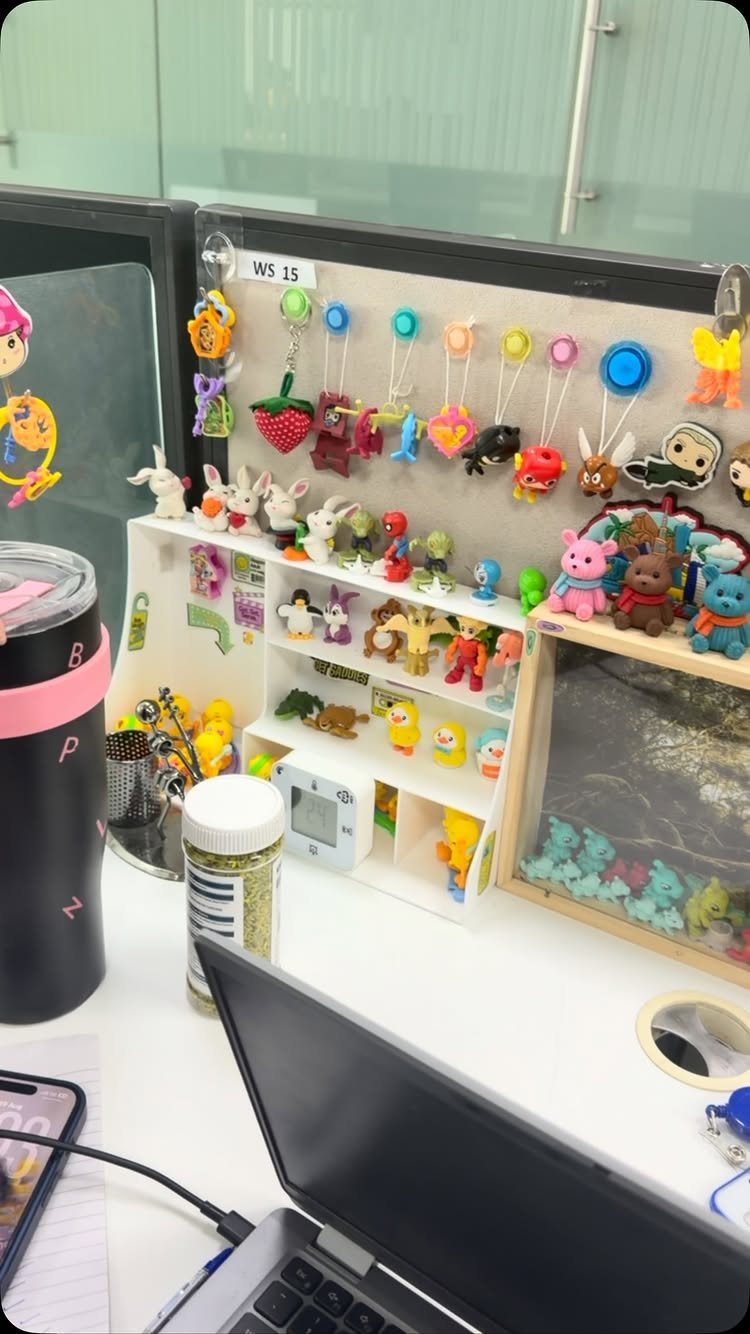 White office desk with colorful figurines on a shelf and charms on the wall.