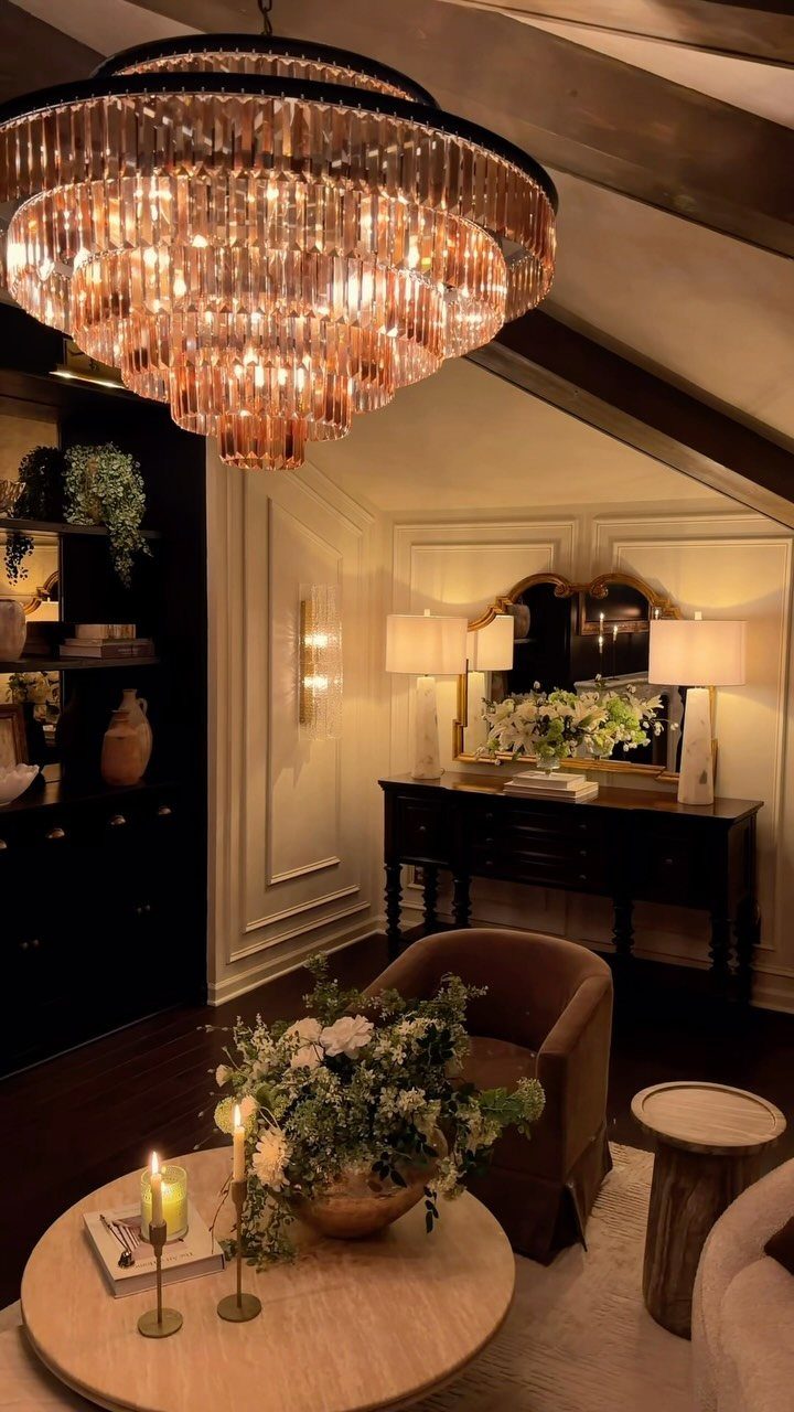 Luxurious room with layered lighting including a crystal chandelier, lamps, and candles.