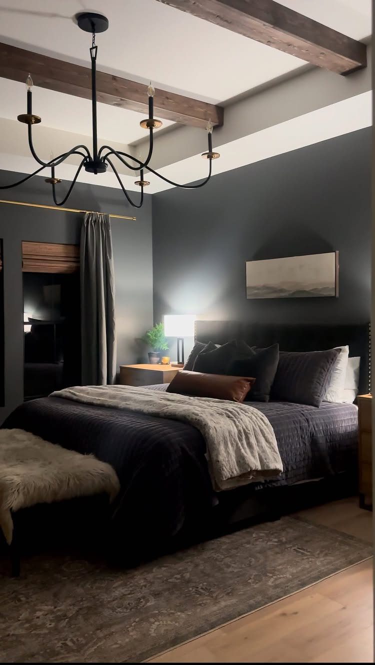Dark charcoal grey bedroom walls with a bed, black chandelier, and wooden beams.