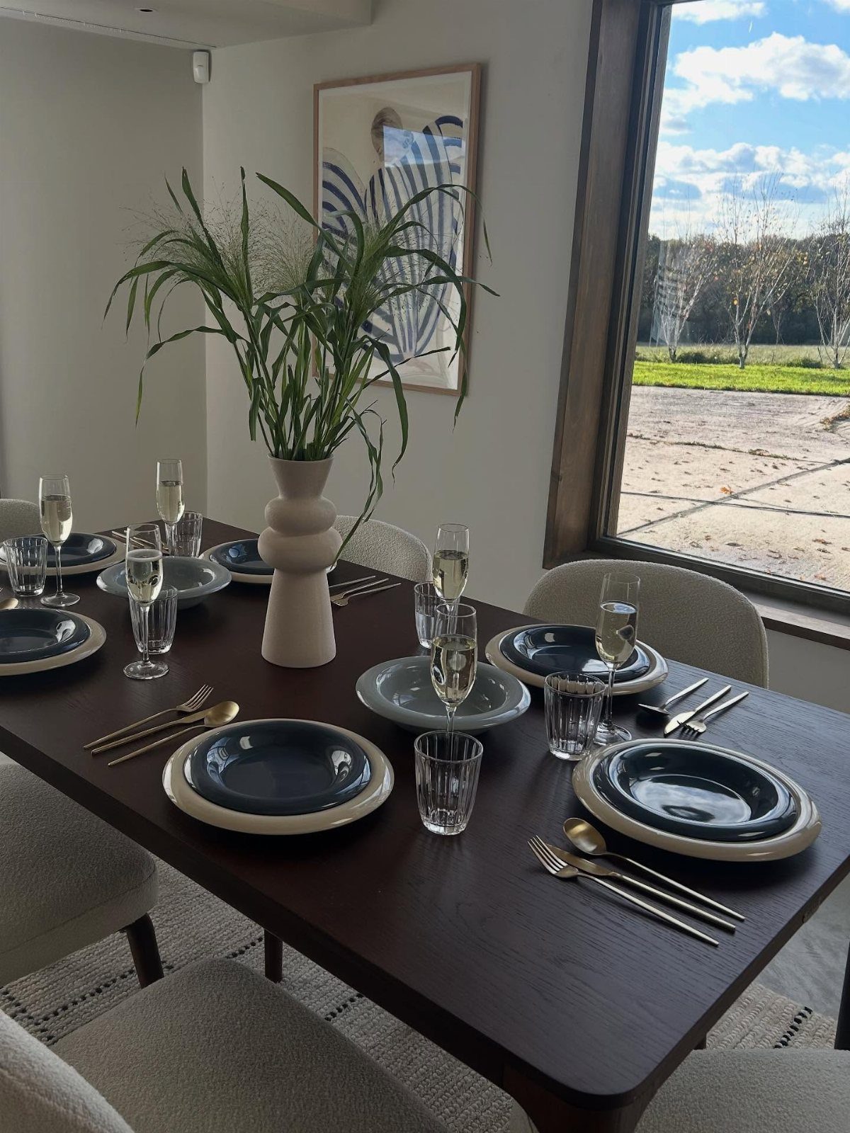 Dark wood dining table set with blue plates and a green plant centerpiece.