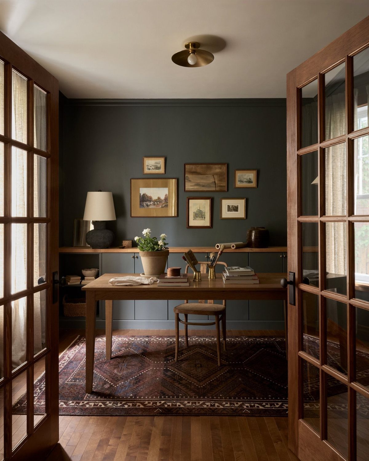 Dark wood desk and French doors in a room with dark grey walls