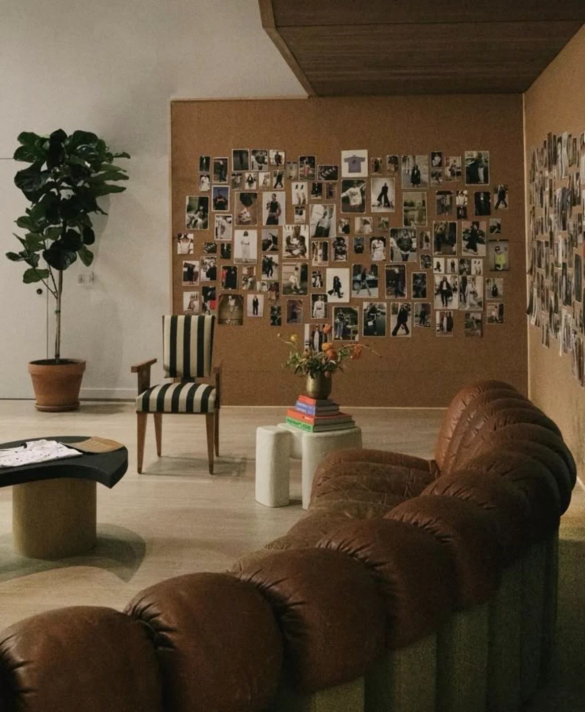 Corkboard wall covered in photos in a modern living room with leather sofa.