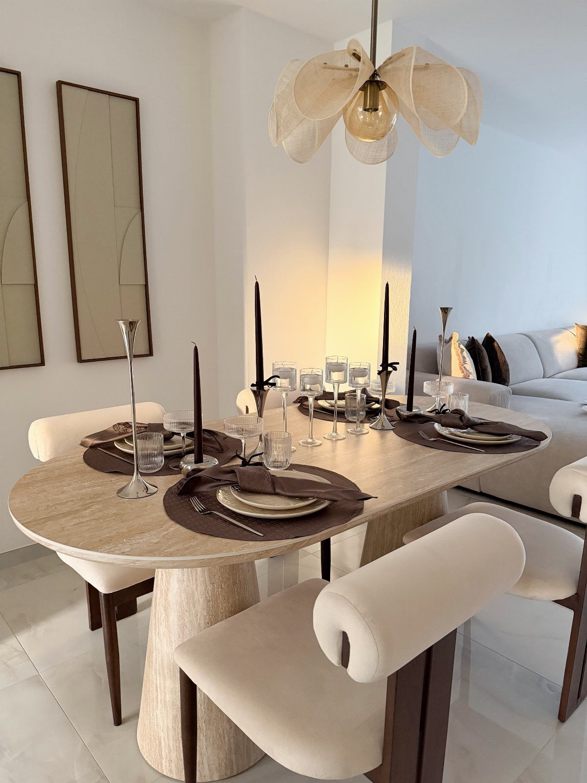 Oval stone dining table set with brown linens and tall black taper candles.